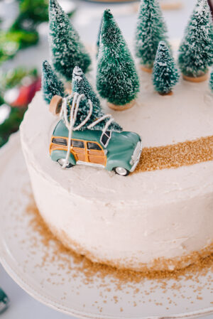 Gingerbread cake with buttercream frosting, Christmas trees, and a station wagon on white cake plate